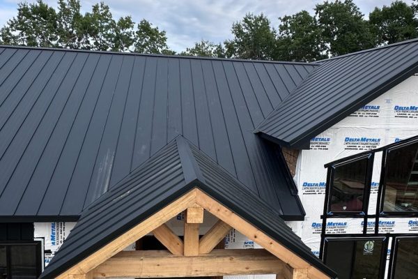 House under construction with a black standing seam metal roof featuring raised interlocking seams for durability, weather resistance, and a clean modern appearance.