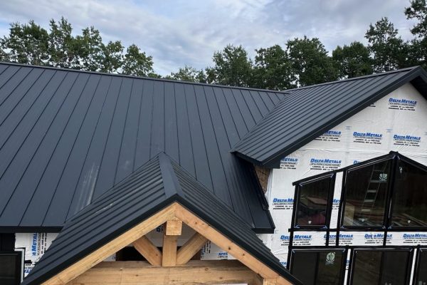 House under construction with a black standing seam metal roof featuring raised interlocking seams for durability, weather resistance, and a clean modern appearance.