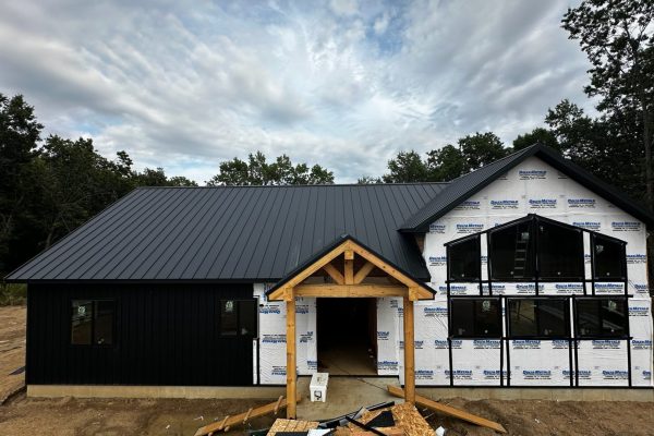 House under construction with a black standing seam metal roof featuring raised interlocking seams for durability, weather resistance, and a clean modern appearance.