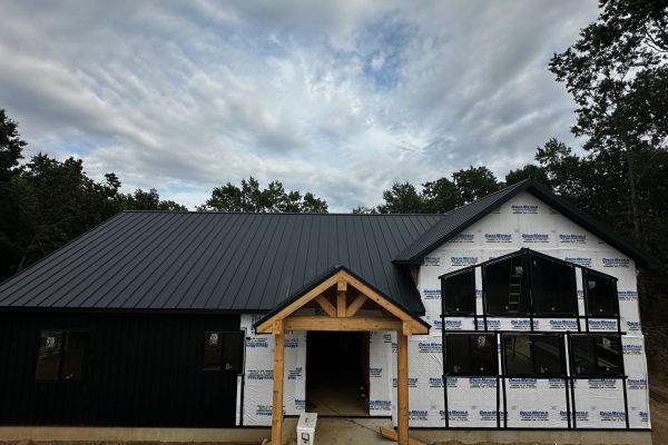 House under construction with a black standing seam metal roof featuring raised interlocking seams for durability, weather resistance, and a clean modern appearance.