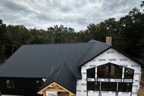 House under construction with a black standing seam metal roof featuring raised interlocking seams for durability, weather resistance, and a clean modern appearance.