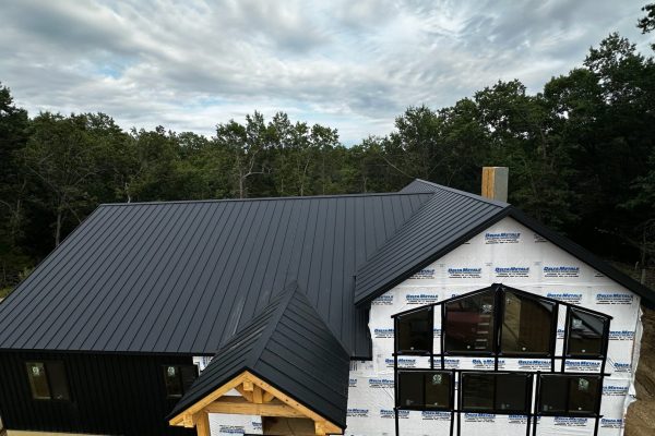 House under construction with a black standing seam metal roof featuring raised interlocking seams for durability, weather resistance, and a clean modern appearance.