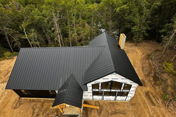 House under construction with a black standing seam metal roof featuring raised interlocking seams for durability, weather resistance, and a clean modern appearance.