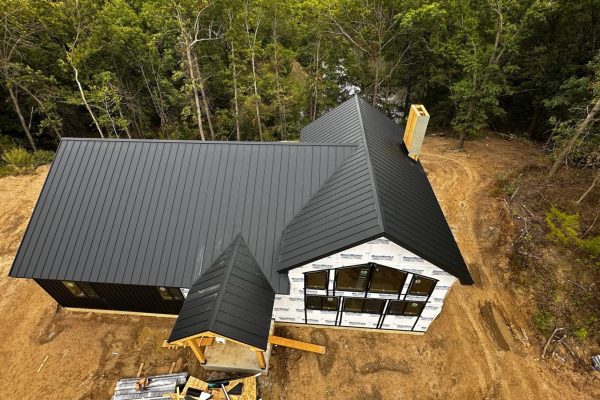 House under construction with a black standing seam metal roof featuring raised interlocking seams for durability, weather resistance, and a clean modern appearance.
