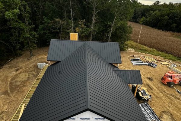 House under construction with a black standing seam metal roof featuring raised interlocking seams for durability, weather resistance, and a clean modern appearance.