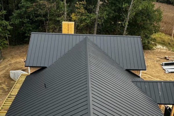 House under construction with a black standing seam metal roof featuring raised interlocking seams for durability, weather resistance, and a clean modern appearance.