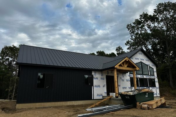 House under construction with a black standing seam metal roof featuring raised interlocking seams for durability, weather resistance, and a clean modern appearance.