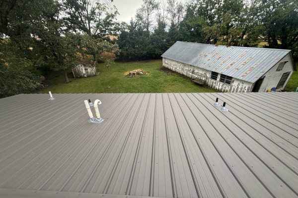 Building with a newly installed tan metal roof featuring ribbed or standing seam panels for long-lasting, low-maintenance weather resistance.
