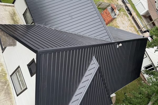 Two-story house with a newly installed black metal roof, likely completed by KM Roofing Solutions LLC.