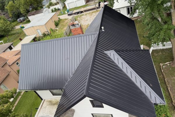 Two-story house with a newly installed black metal roof, likely completed by KM Roofing Solutions LLC.