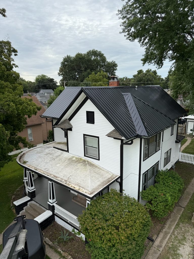 Two-story house with a newly installed black metal roof, likely completed by KM Roofing Solutions LLC.