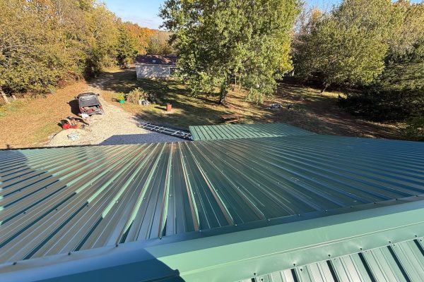 Newly installed green metal roof on a residential building featuring interlocking metal panels for long-lasting, energy-efficient performance.