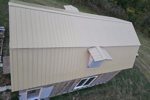 Building with a newly installed tan metal roof featuring ribbed or standing seam panels for long-lasting, low-maintenance weather resistance.