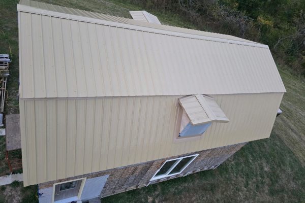Building with a newly installed tan metal roof featuring ribbed or standing seam panels for long-lasting, low-maintenance weather resistance.