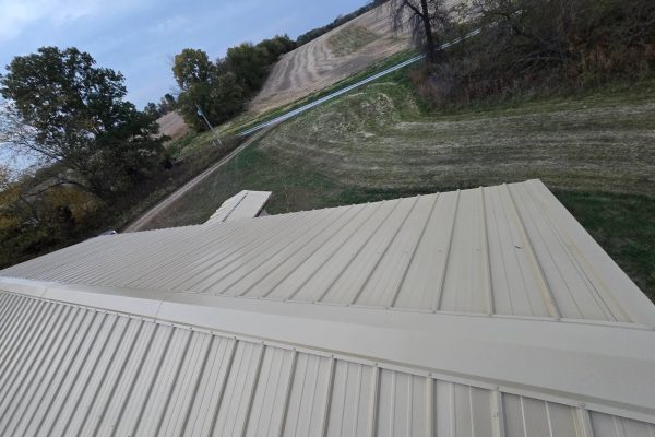 Building with a newly installed tan metal roof featuring ribbed or standing seam panels for long-lasting, low-maintenance weather resistance.