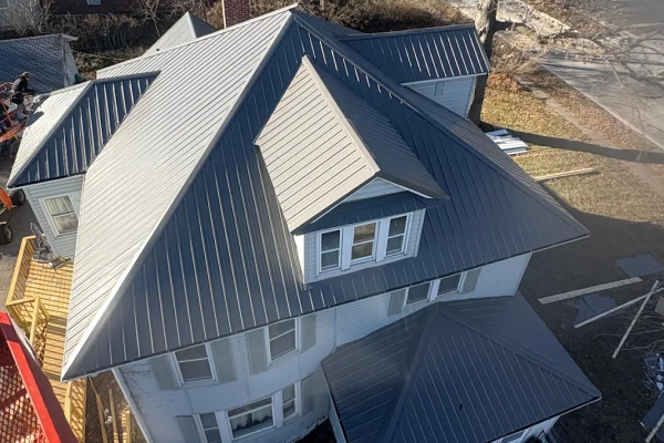 House with a newly installed dark gray standing seam metal roof featuring concealed fasteners for long-lasting, weather-resistant performance and energy efficiency.